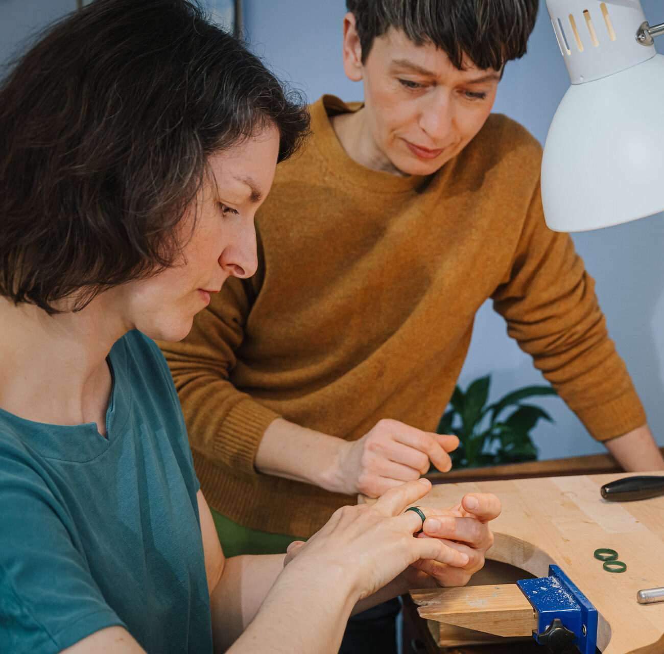Zwei Personen nehmen an einem Goldschmiede Schmuckkurs / Trauringkurs in der Schmuckwerkstatt Schimmer Goldschmiede in Halle /Saale bei Annekathrin Pohle Sophie Baumgärtner, Charlotte Antony teil. Die Frau im grünen Oberteil wird von der Kursleiterin beraten.